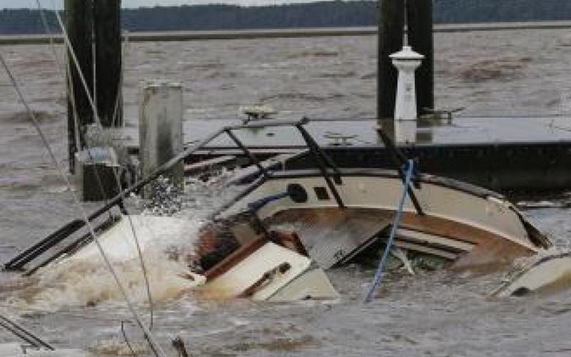 A partially submerged boat near dock pillars in a choppy water setting.