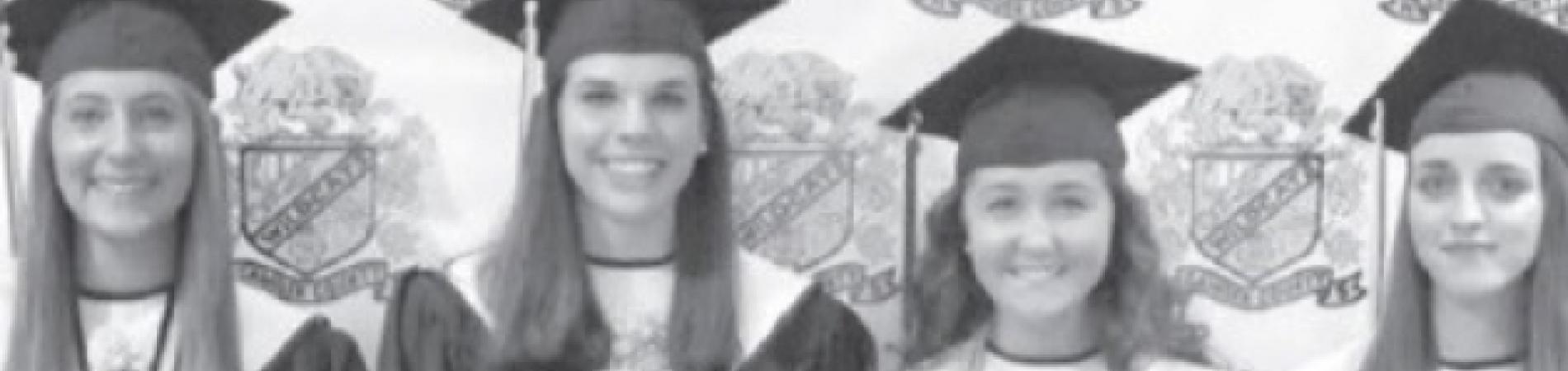 Graduates in caps and gowns hold diplomas, smiling in a black-and-white photograph.
