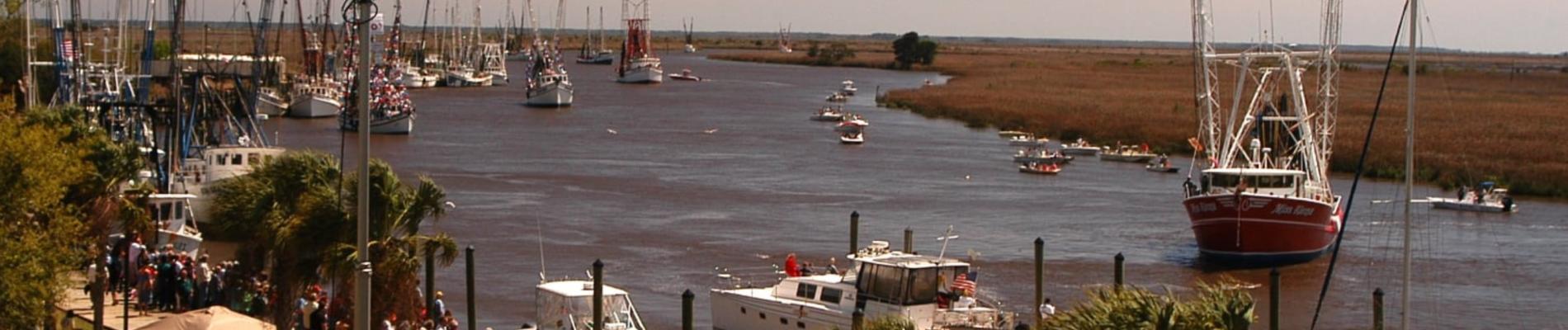 Boats on a calm river with grassy banks and a distant marshland background.