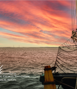 Sunset over ocean with partial view of a sailboat on the right.
